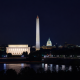 The Washington DC skyline at night with the reflecting pool in the foreground. The US Capitol, Washington Monument and Lincoln Memorial are visible.